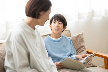 本を読む男の子とソファに座る母親