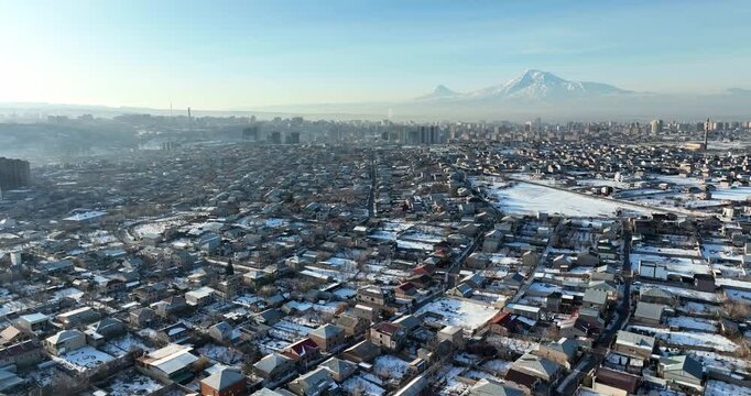 Aerial view of a village in Armenia in winter, with snow-covered roads and cars driving