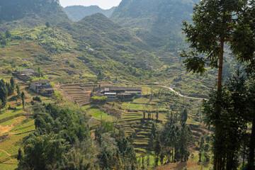 Village and terraced fields spread across green mountainside valley.