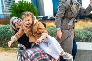 Granddaughter visiting grandmother in wheelchair during outdoor walk