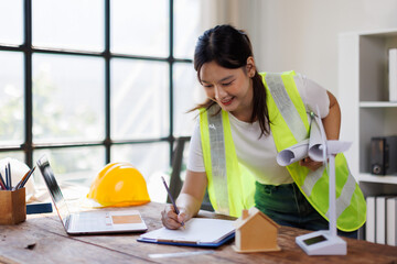 Architect using calculator with engineer reviewing blueprint for a tiny house project. Architect...