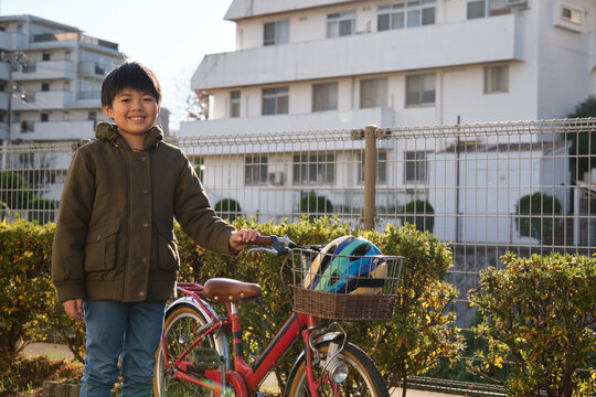 Smiling child with bicycle and helmet outdoors in residential area