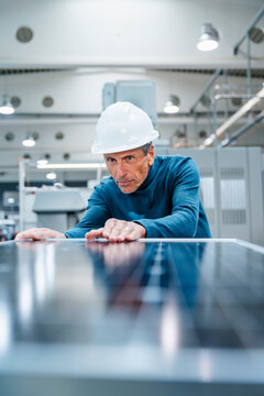 Senior engineer examining solar panel at industry