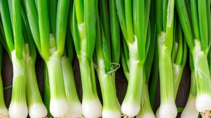Obraz premium Fresh Green Onions Stacked on Brown Wooden Surface Perfect for Cooking and Culinary Use in Various Dishes