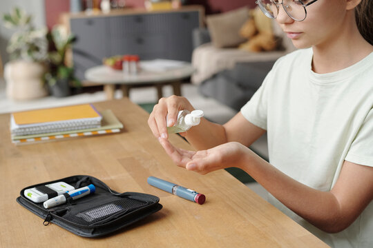 Person sanitizing hand at home with glucometer and insulin pen on table