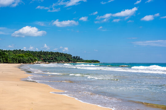 Tropical Mawella Beach with sand waves and blue sea in Sri Lanka