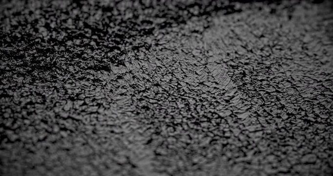 Macro Cracked Mud Texture on Black. Slow panning footage across a fissured dark surface, showcasing intricate polygonal crack patterns and rough granular details under subtle directional lighting.