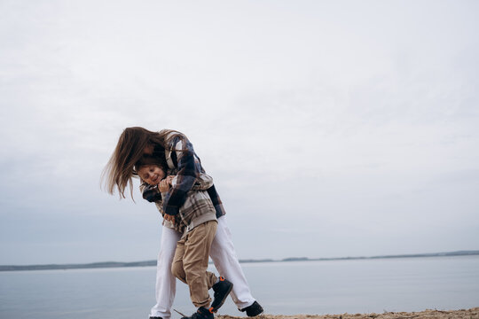 Mother hugging son on lakeshore outdoors in autumn