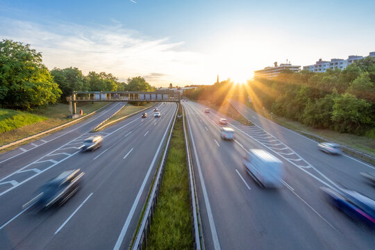 Cars and vehicles moving on highway in city at sunset