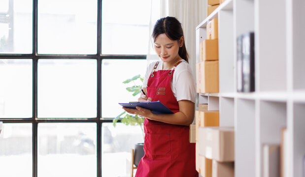 Smart Asian millennial female online business owner checking hier sme product stocks in the stock room. SME startup business entrepreneur.
