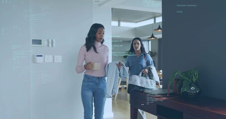Naklejka premium Entering two women in entry, one wearing pink sweater, carrying mug and duffel, code overlay