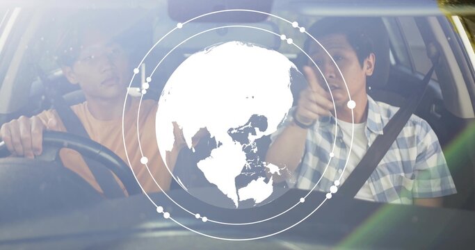 Pointing passenger in checked shirt guiding driver in peach tee holding wheel in car with globe