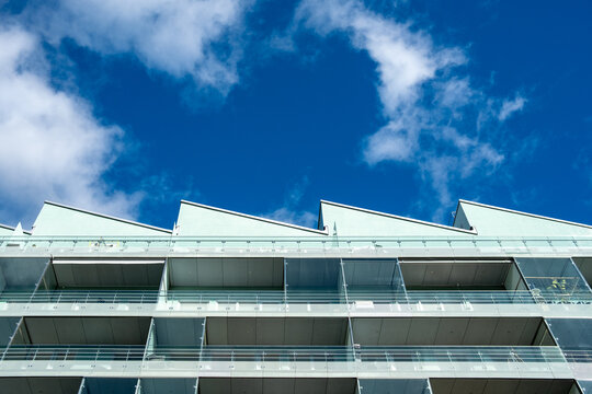 Balcony facade meets dramatic sky as modern residential apartment architecture rises in Stockholm Sweden with clouds and clear daylight atmosphere