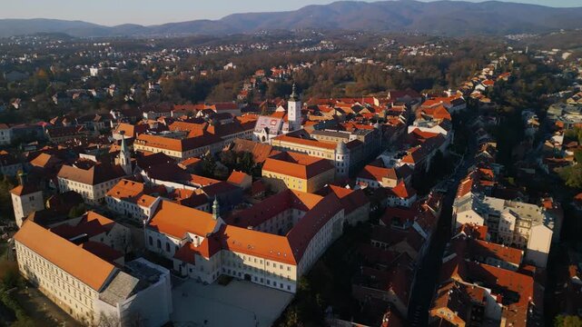 Cinematic 4K aerial orbit of St. Mark's Church and Upper Town in Zagreb. Historic orange roofs and parliament building at sunset, Croatia.