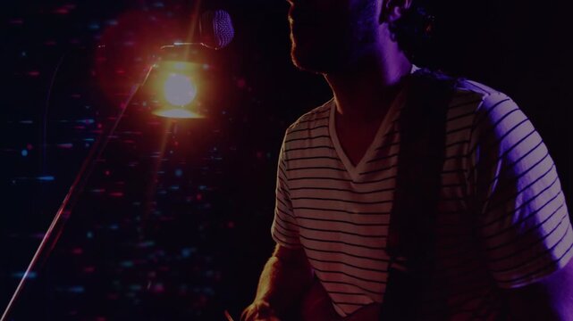 Camera pulling back as musician fretting red guitar, leaning to mic under warm backlight, singing