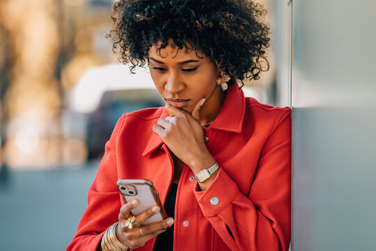 woman on the street, using her cell phone, suspicious and hesitant