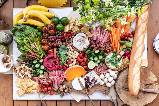 Vibrant catering spread on a wooden table at a campsite near Lake Yamanaka. Healthy grazing board with fresh fruits, vegetables, dips, and cheeses for a glamping event.