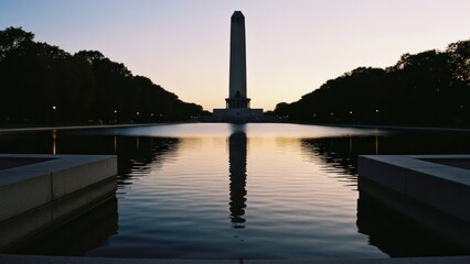 Obraz premium Monument reflects in pool, framed by symmetrical ledges, trees under soft twilight sky