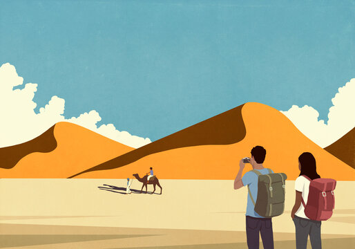 Tourist couple with camera in desert landscape photographing people with camel travel