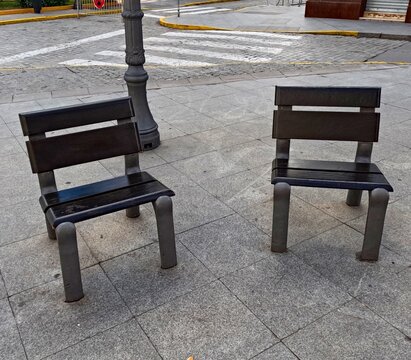 Two empty public benches in a town square in Dos Hermanas, Seville, representing everyday life, waiting, rest and calm in a traditional Andalusian urban environment