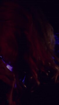 Vertical video: Woman singer emerging as purple light sweep showing face with mic and singing music