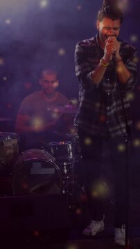 Vertical video: Light cue cueing singer with mic leaning, drummer keeping beat, glow framing music