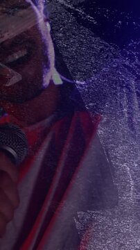 Vertical video: Grain fading, music artist emerging, singing into mic under purple red overlay