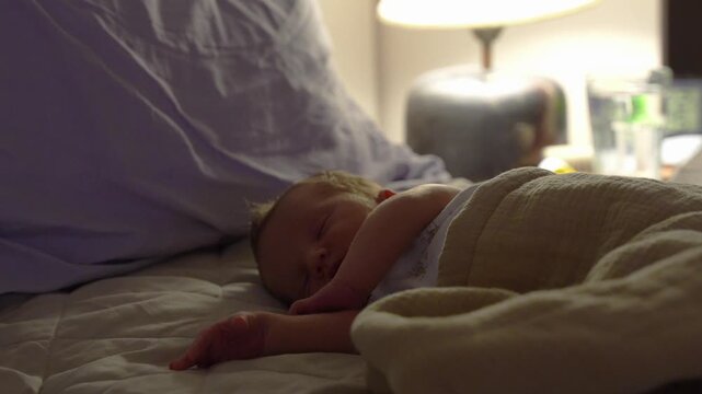 newborn baby sleeping on a bed at night