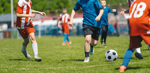 Obraz premium Youth Soccer Game Action; Children Competing for Ball During Outdoor Football Match