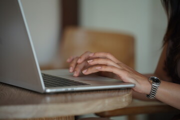 Close-up of hands typing on a laptop keyboard, remote work or digital nomad lifestyle.