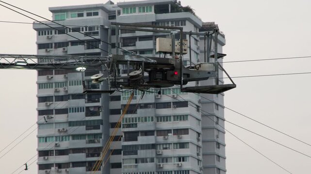 Industrial Cable Maintenance Equipment Moving Along Wires Near High Rise Apartment
