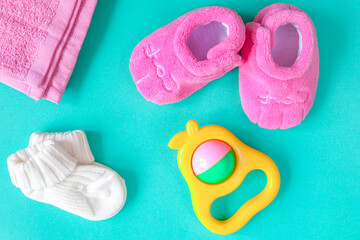 children's clothes and baby booties on green background