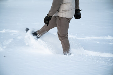 Person Kicking Up Powder Snow While Walking Through Winter Landscape In Warm Clothing And Gloves