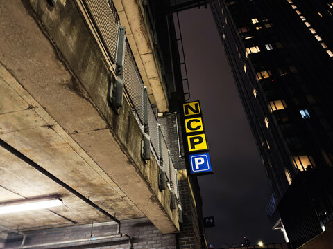 Night scene in Manchester street with NCP parking signs on a concrete building