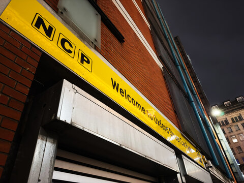 Welcome to Manchester UK street entrance with yellow NCP signage and brick building at night