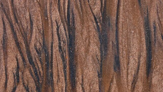 Magical with Black Sand Beaches on multicolored Hormuz Island, Iran. The dark sand from heavy minerals such as hematite, ilmenite, and magnetite, creating striking textures along the shoreline.