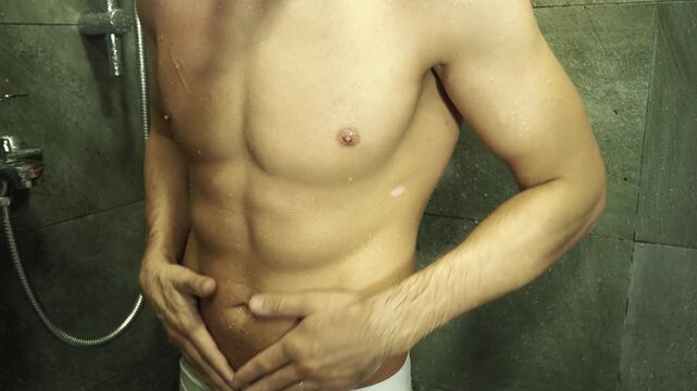 An athletic man takes a shower 