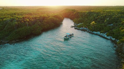 Boat anchored in narrow tropical lagoon with dense jungle in Mexico at sunset. © Olga Gorkun