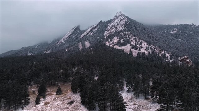 Flat Irons Mountain Winter Chautauqua Park trail aerial drone Boulder Colorado USA snowing dusk sunset low clouds grass snow covered Rock formation walking loop Bear Peak circle right motion