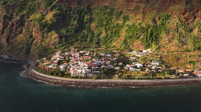 Sunset aerial view of Jardim do Mar on western Madeira below lush towering cliff