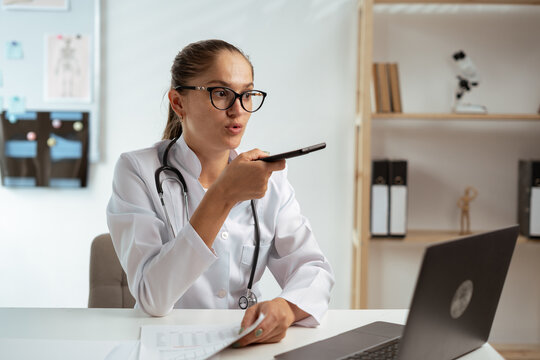 Young female doctor command to ai assistant in medicine to search medical information, voice message calling patient by phone