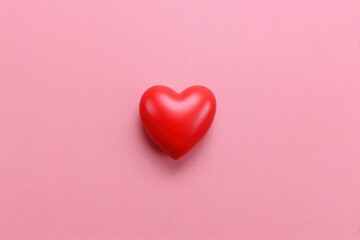 Fototapeta premium Vibrant red heart on soft pink background symbolizing love and affection