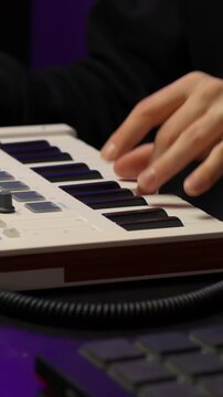 Close-up of hands playing a MIDI keyboard for music production, vertical shot