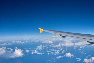 Fototapeta premium Airplane wing cutting through the airspace above an endless horizon of cottony clouds during a long journey
