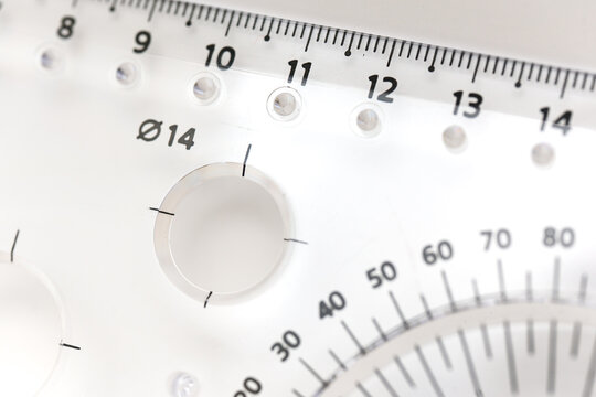 Measuring tool on a table with clear markings and holes for circles