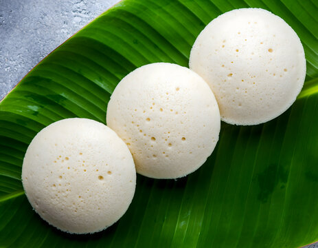 three soft idlis arranged on banana leaf representing traditional indian breakfast