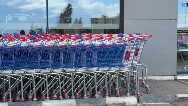 Row of shopping carts lined outside supermarket entrance in urban area. Shopping carts reflect daily retail routine, shopping carts show consumer flow order and express modern city shopping habits