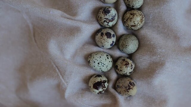 Quail eggs are placed closely together on a light cloth, showing their natural colors and patterns in the light.