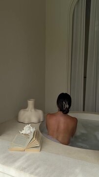 Serene bathing moment in a sunlit Bali villa bathroom with soft neutral tones and spa aesthetic.