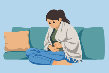 Woman sitting on sofa wrapped in blanket feeling unwell or cold.